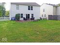 Lush green backyard featuring a patio area, a fire pit, and privacy fencing at 10316 Hatherley Way, Fishers, IN 46037