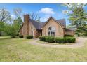 A well landscaped home with a stone chimney and arched window above the entrance at 10602 Fall Rd, Fishers, IN 46037