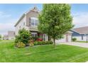 Charming two-story home featuring a brick facade, three-car garage, manicured lawn, and lush landscaping at 15143 Gallop Ln, Fishers, IN 46040
