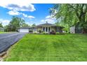 Scenic view of a well-kept ranch house with green lawn and a detached garage, under a bright sky at 169 Bayview Dr, Cicero, IN 46034