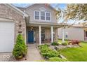 Inviting front porch featuring a seating area, landscaping, and a vibrant blue front door at 1815 Kingen Dr, Greenfield, IN 46140