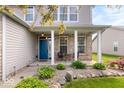 Welcoming front porch with a seating area surrounded by lush landscaping and a bright blue door at 1815 Kingen Dr, Greenfield, IN 46140