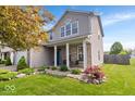 Charming two-story home features a covered porch with seating and well-maintained landscaping at 1815 Kingen Dr, Greenfield, IN 46140