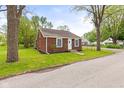 Quaint brick home showcasing green lawn, trees, and inviting curb appeal on a sunny day at 2321 W 26Th St, Anderson, IN 46016
