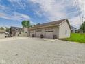 Detached garage with three bays and decorative barrels in front of doors, surrounded by a gravel parking pad at 238 Jefferson St, Pendleton, IN 46064