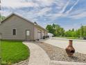 Detached three-bay garage with a paved walkway, decorative barrels, and ample parking space at 238 Jefferson St, Pendleton, IN 46064