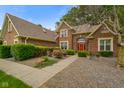 Beautiful brick home featuring a manicured lawn, mature trees, and a welcoming red front door at 2508 Indian Creek Rd, Trafalgar, IN 46181