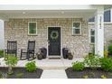 Welcoming front porch featuring stone accents, rocking chairs, and decorative planters at 2542 Barstow Dr, Whitestown, IN 46075
