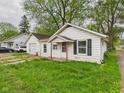 Cozy single-story home with attached garage surrounded by green grass and mature trees at 29 E Pine St, Anderson, IN 46012