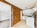 Functional kitchen with essential appliances adjacent to a room with worn carpet at 29 E Pine St, Anderson, IN 46012