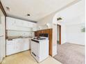 Compact kitchen featuring essential appliances and a view into a carpeted adjacent room at 29 E Pine St, Anderson, IN 46012