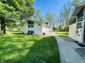 Exterior of the home featuring a pathway and a well-manicured lawn, with lush greenery all around at 3081 Woodridge Rd, Shelbyville, IN 46176