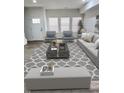 Bright living room featuring a gray sofa, chairs, ottoman, a decorative rug and large windows at 3811 N Lawndale Ave, Indianapolis, IN 46254