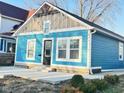 Light blue bungalow featuring a well-manicured yard and white trim around the windows at 424 S Parker Ave, Indianapolis, IN 46201