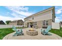 Spacious backyard patio featuring a fire pit, outdoor seating, and lush green lawn at 4763 W Tradwell Dr, New Palestine, IN 46163