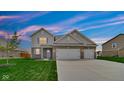 Charming two-story home featuring a well-manicured lawn, brick accents, and an attached two-car garage at 4763 W Tradwell Dr, New Palestine, IN 46163