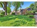 Spacious lawn with mature trees, showcasing a charming brick home with a classic chimney at 5034 N Capitol Ave, Indianapolis, IN 46208