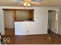 Open living room featuring wood-look flooring, a ceiling fan, and view into the kitchen and bathroom areas at 909 Hickory St, Anderson, IN 46012