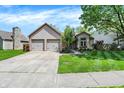 Inviting home featuring a two-car garage, lush green lawn, and established trees at 9255 Fireside Dr, Indianapolis, IN 46250