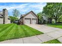 Home with a two-car garage, and a well-maintained lawn, side chimney, and established trees at 9255 Fireside Dr, Indianapolis, IN 46250