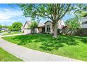 Attractive home with a spacious front yard, mature tree, and a two-car garage at 9255 Fireside Dr, Indianapolis, IN 46250