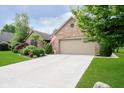 Well-maintained brick home featuring a clean concrete driveway and a beautiful landscaped front yard at 10833 Tournament Ln, Indianapolis, IN 46229
