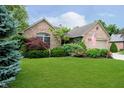 Beautiful brick home with a lush green lawn and colorful landscaped garden beds in front at 10833 Tournament Ln, Indianapolis, IN 46229