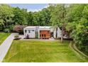 Aerial view of a modern home with lush landscaping, long driveway, and wooded backdrop at 11911 Eden Glen Dr, Carmel, IN 46033