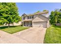 Two-story home with brick details, a two-car garage, a well-kept lawn, and mature trees under a clear blue sky at 1238 Aggie Ln, Indianapolis, IN 46260