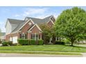 A well-maintained brick home featuring a manicured lawn and mature trees offering substantial curb appeal at 13234 Amundson Dr, Carmel, IN 46074