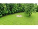 Aerial view of the sprawling lawn featuring a cozy fire pit with yellow chairs nestled amongst the trees at 1409 S Northview Dr, Martinsville, IN 46151