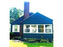 Charming blue home featuring a brick chimney, white-framed windows, and neatly landscaped front yard at 310 S Butler Ave, Indianapolis, IN 46219