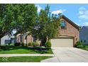 A well-maintained home with a lush green lawn, mature trees, and an attached two-car garage at 5047 Skipping Stone Dr, Indianapolis, IN 46237