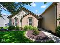 Charming home featuring a well-manicured front yard with lush green grass and mature landscaping at 5047 Skipping Stone Dr, Indianapolis, IN 46237