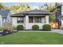 Classic white brick home with vibrant red door, neatly landscaped lawn, and inviting front porch, exuding warmth at 6167 Carrollton Ave, Indianapolis, IN 46220