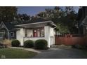 Quaint white brick home with a red door, complemented by lush greenery and a driveway, offering curb appeal at 6167 Carrollton Ave, Indianapolis, IN 46220