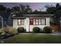 Charming white brick home featuring a bright red front door, a covered porch, and beautifully manicured landscaping at 6167 Carrollton Ave, Indianapolis, IN 46220