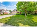 Inviting home with a lush green lawn, mature tree, and a spacious driveway leading to a three-car garage at 7023 Hartington Pl, Indianapolis, IN 46259