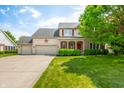 Traditional home with a well-kept lawn, three-car garage, and a welcoming front porch at 7023 Hartington Pl, Indianapolis, IN 46259