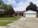 Single story brick home featuring an attached two car garage and a large front yard at 7764 Hollybrook Ln, Southport, IN 46227
