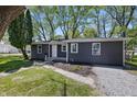 Quaint single-story house with gray siding, white windows, landscaping, a walkway, and a gravel driveway at 807 Vasbinder Dr, Chesterfield, IN 46017
