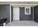 Close-up of the front porch showcasing the entrance door, house number, a light fixture, and gray horizontal siding at 807 Vasbinder Dr, Chesterfield, IN 46017