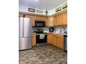 Well-lit kitchen features stainless steel appliances, wood cabinetry, and dark stone-look flooring at 8410 Woodlawn Dr, Martinsville, IN 46151