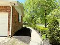 Side yard featuring a brick exterior, green trees, and a concrete walkway with mulch beds at 8835 Briarclift Rd, Indianapolis, IN 46256