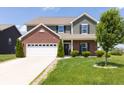 Two-story home featuring green siding, brick accents, an attached two car garage and a well-manicured front yard at 928 Cherry Tree Ln, Greenwood, IN 46143