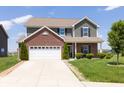 Two-story home featuring green siding, brick accents, an attached two car garage and a well-manicured front yard at 928 Cherry Tree Ln, Greenwood, IN 46143