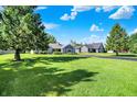 View of the home with lush lawn and mature trees providing shade and privacy at 12681 E 79Th St, Indianapolis, IN 46236