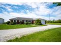Ranch style home with brick facade, attached garage, large yard, and long gravel driveway at 133 W Us Highway 52, Fountaintown, IN 46130