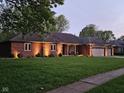 A single-story brick home on a lush green lawn with mature trees in a quiet neighborhood at 1515 Renee Dr, Plainfield, IN 46168