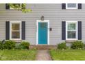 Close up view of the front of the house featuring a bright blue front door with black shutters and landscaping at 2336 Sycamore St, Columbus, IN 47201